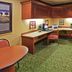 The Q Hotel & Suites in Springfield work area with L-shaped desk, chairs, wood cabinets and green carpet