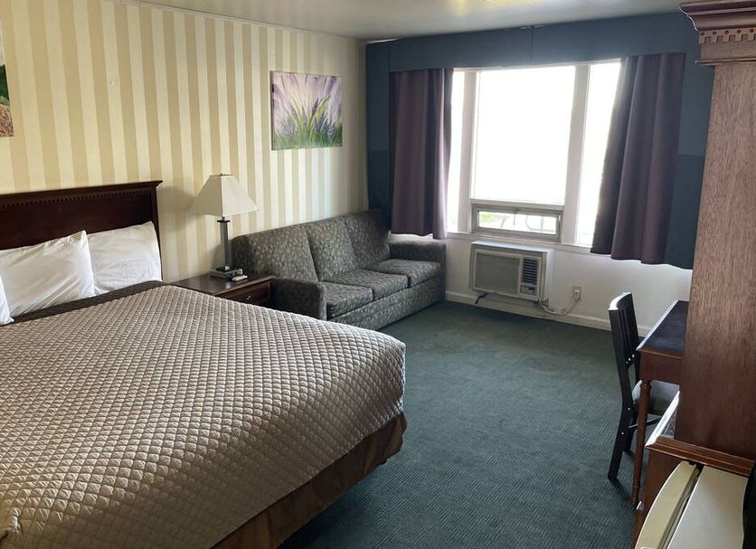 Motel Oasis in Moses Lake guest room with king bed, sofa, desk and window air conditioner