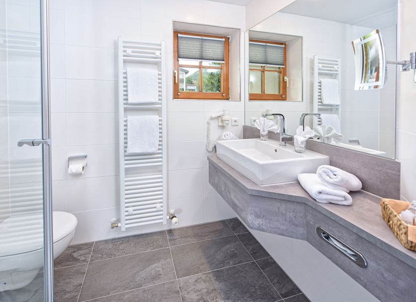 Concordia Vitalhotel & Spa bathroom in Oberstaufen with shower, sink, mirror and towel warmer