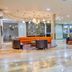 Howard Johnson by Wyndham Barranquilla Versalles lobby with orange sofa, lounge chairs and mosaic wall in Barranquilla
