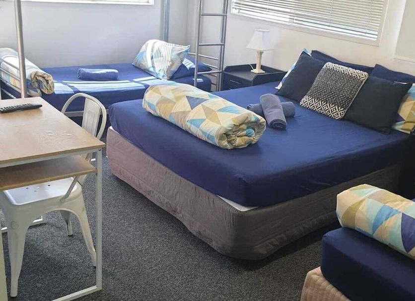 Backpackers Central Hamilton room with multiple single beds, desk, and window blinds in Hamilton