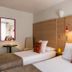 Hôtel Edmond Rostand Marseille guest room with twin beds, wood-paneled wall, and colorful accent pillows