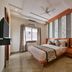 Hotel Yois Udaipur bedroom with king bed, wood paneling, ceiling fan and window light