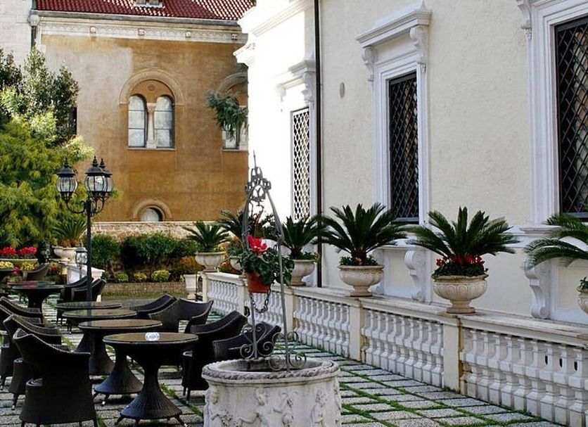 Hotel Villa Pinciana in Rome courtyard with outdoor seating, potted palms, and historic building facade