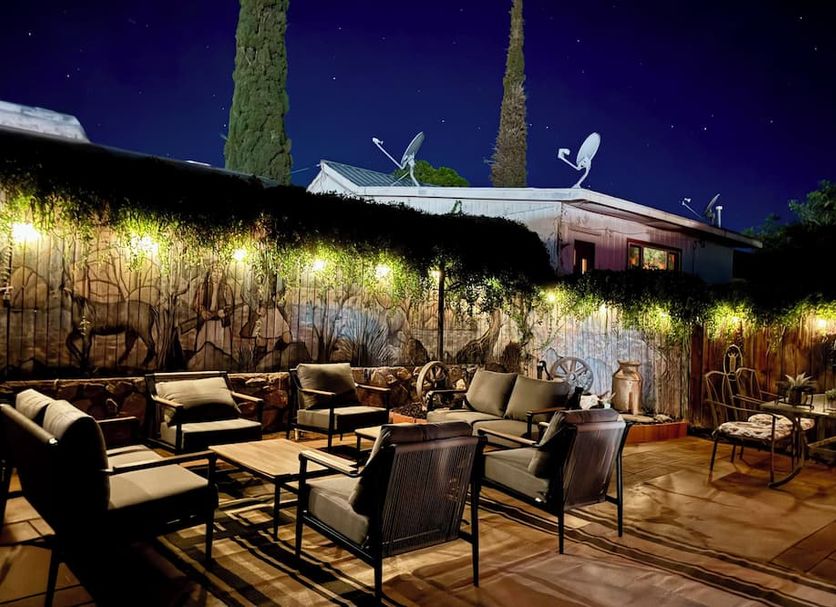Trail Rider's Inn in Tombstone patio seating under string lights with tall trees and evening sky