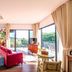 Rain Tree Khao Yai Hotel in Pak Chong living area with red sofa, large windows and balcony views