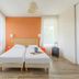Appart'City Confort Tours twin bedroom with orange accent wall and suitcase by the window