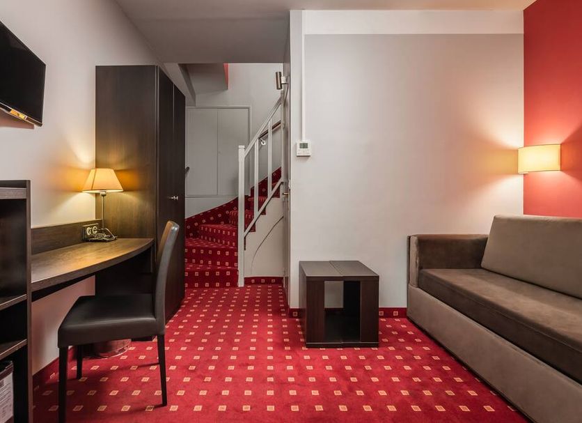 Hotel Des Deux Avenues, Paris guest room with red carpet, desk, sofa, and staircase