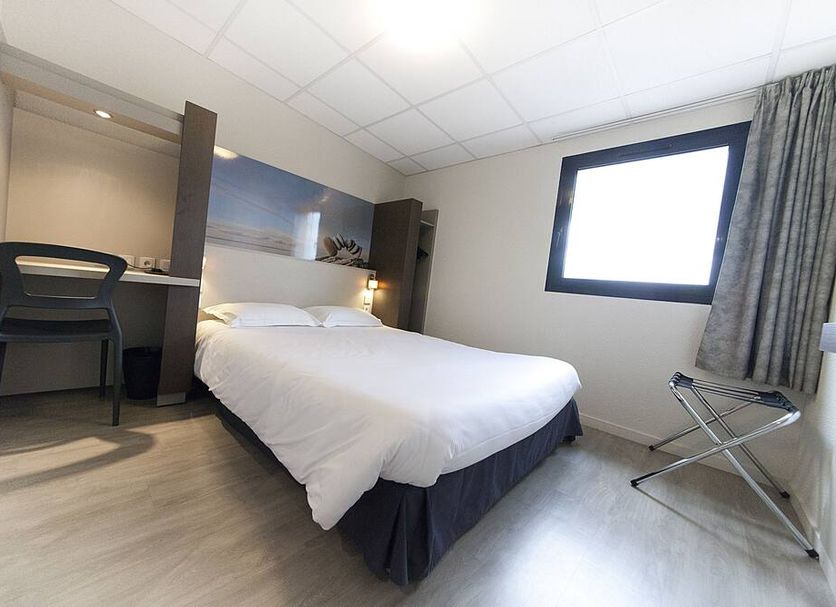 Fasthôtel Clermont sud in Aubière: compact hotel room with bed, desk, chair, window and luggage rack