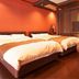 Houraiya, Kamogawa: twin beds in a warm-toned guest room with a brown lounge chair