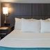 Paynesville Inn And Suites in Paynesville guest room with neatly made bed and wall-mounted lamps