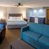 Paynesville Inn And Suites guest room with king bed, teal sofa, and black lounge chair in Paynesville
