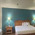 Motel 6 Portland, IN guest room with king bed, nightstands, teal accent wall, lamps and TV