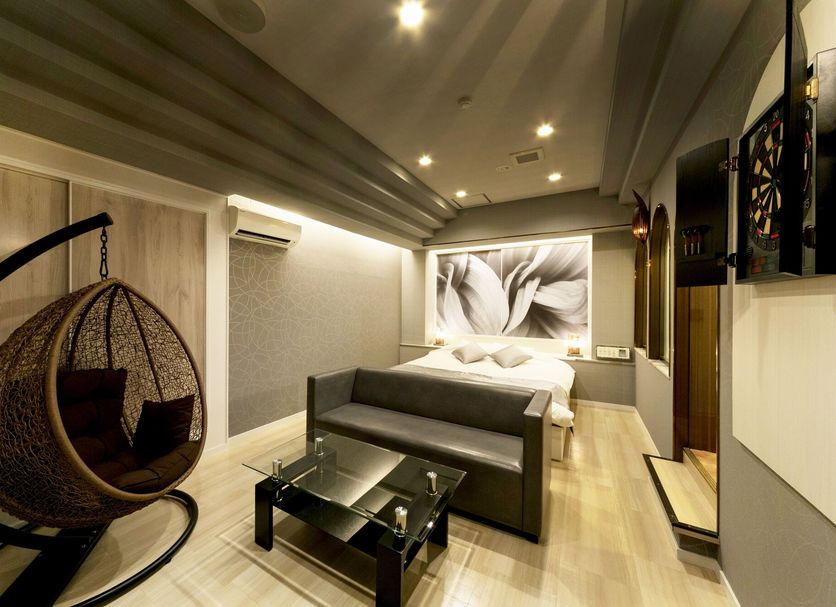 Hotel Lotus Sakai adult-only room with hanging chair, sofa, glass coffee table and wall art in Sakai