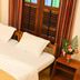 Sea Shell Haris Beach Home, Kannur: cozy bed beside wooden shutters and a small bedside table with flowers.