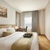 Grand Serela Yogyakarta guest room with king bed, desk, wall-mounted TV and window curtains