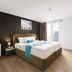 Hotel Mika Downtown Budapest guest room with double bed, bedside lamps, balcony door, and minimalist decor