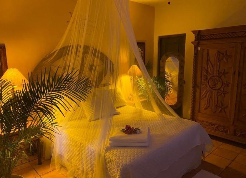 The Mexican Inn in Cabo San Lucas bedroom with canopy bed, mosquito net, warm lamps and carved wardrobe