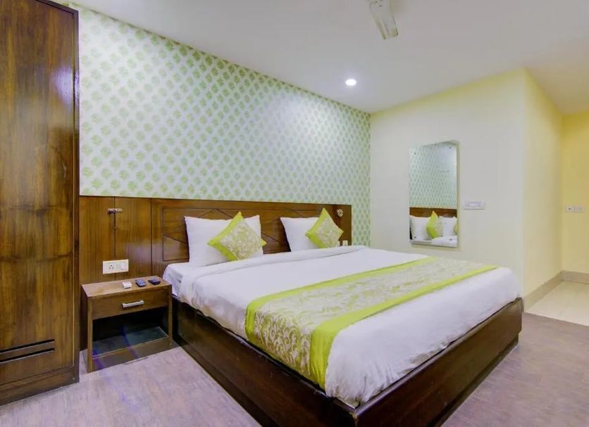 Hotel Daya Continental, New Delhi: double bed in a guest room with wood headboard and mirror