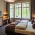 Upstalsboom Heringsdorf room with double bed, desk, TV and large windows overlooking greenery