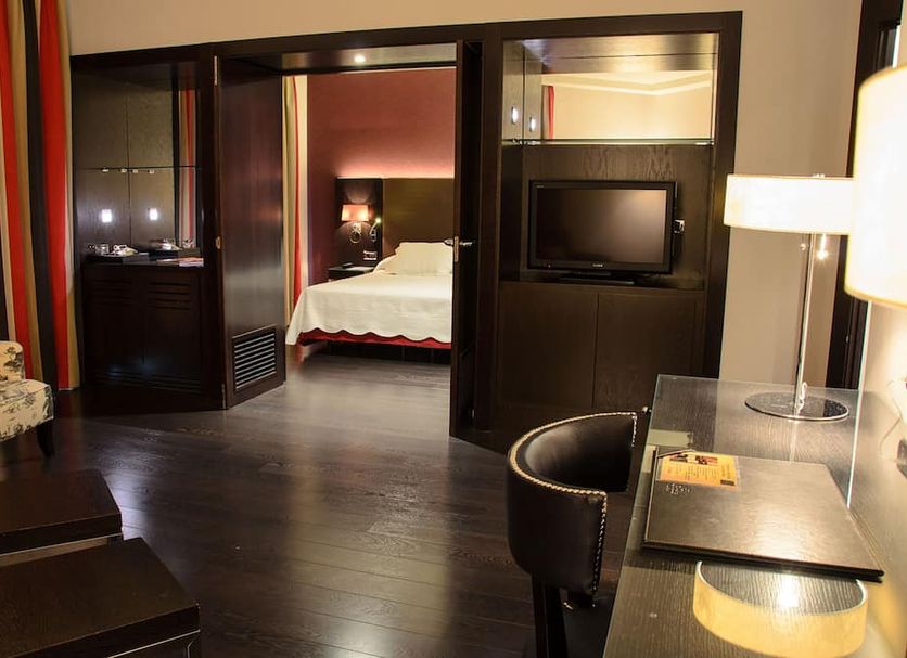 Hotel Boutique Gareus in Valladolid: stylish hotel room with bedroom, TV, desk, and armchair