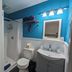 Riverboat Inn and Suites Madison bathroom with shower, toilet, sink, and bright blue accent wall