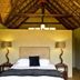 Pilanesberg Private Lodge guest room with thatched ceiling, king bed and bedside lamps in Pilanesberg