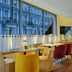 The Cura Hotel Kensington, London dining room with colorful chairs and large street-facing windows