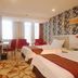Spring Hotel Dalian guest room with two beds, red chairs, desk and patterned accent wall