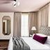 Zelda Dearest Asheville guest room with king bed, mirrored wall accent, dresser, and tall window drapes