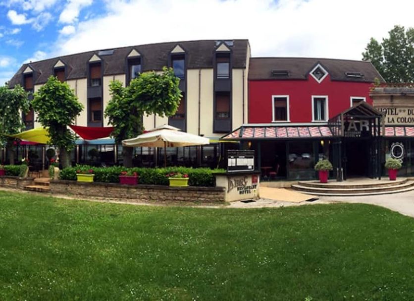 Hotel du Parc de la Colombière in Dijon with a lawn, patio umbrellas, and colorful exterior buildings