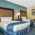 Regency Inn & Suites New London Mystic guest room with two beds, desk, chair, and colorful wall art in New London