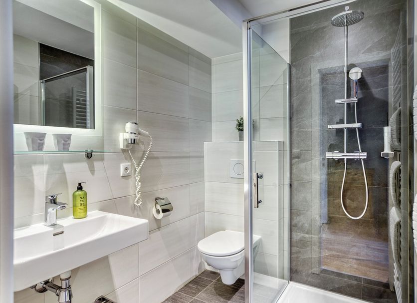 Boutiquehotel Zomm In Seefeld bathroom with glass shower, wall-mounted sink and towel rack