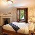 Rokeby Manor in Invergarry guest room with king bed, fireplace, wall-mounted TV, and open window view.