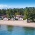 The Beach House in Mackinaw City, beachfront cottages along a sandy shore beside calm blue water.