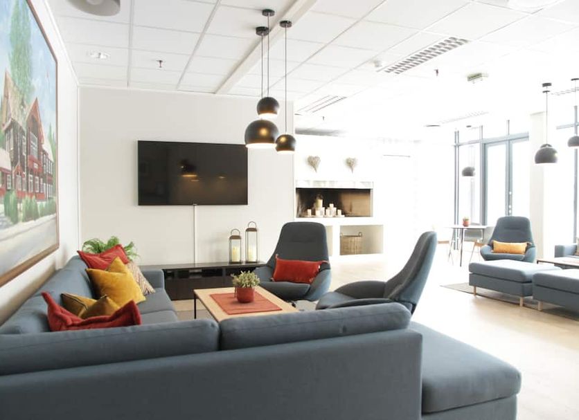 Trudvang Apartment Hotel in Rena living area with gray sofas, wall TV, and pendant lighting