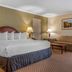 Quality Hotel Conference Center Cincinnati Blue Ash guest room with king bed, sofa, lamps and carpeted seating area in Cincinnati