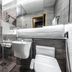 Jamsil Stay Hotel Seoul bathroom with toilet, sink, glass shower and gray tile walls