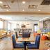 Hampton Inn Crystal River lobby seating area with tables, blue chairs, sofas, and patterned carpet