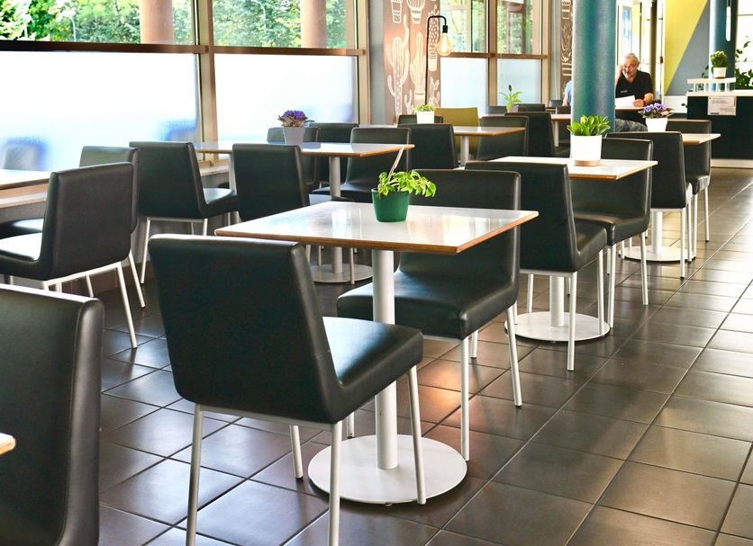 ibis budget Wroclaw Stadion dining area with black chairs and square tables in Wrocław