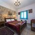 Spot Hotel Rhodes guest room with stone accent wall, double bed, blue-curtained window and tiled floor