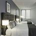 Broadway Plaza Hotel New York guest room with two beds, city view window, desk and wall mirror