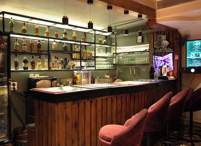 Jullundur Hotel & Restaurant in Chandigarh bar with backlit liquor shelves and pink upholstered stools