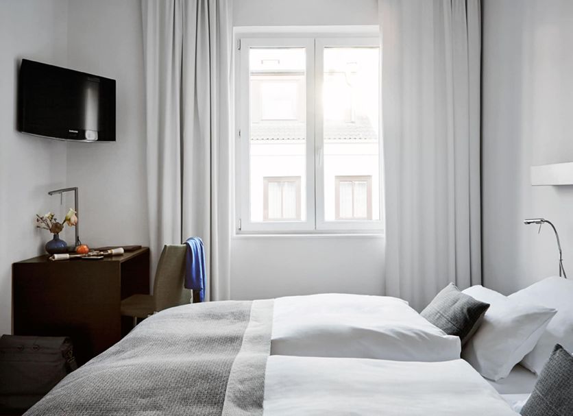 Wedina Budget Hamburg room with twin beds, wall-mounted TV, desk, and bright window