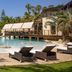 Bahia Del Duque in Adeje with a tropical lagoon-style pool, lounge chairs, and palm trees