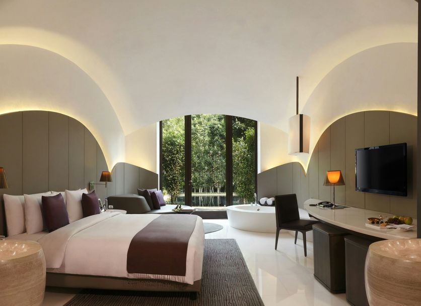 The Roseate New Delhi guest room with arched ceiling, double bed, and garden view