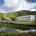 Hotel Katla by Keahotels in Vik beside a pond with green hills and red-roofed buildings