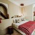 Riad Dar Ayur, Marrakech bedroom with striped bedspread and arched alcove leading to a soaking tub
