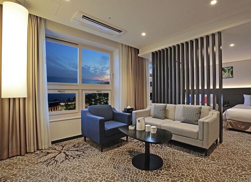 Airsky Hotel Incheon in Incheon guest room with sofa, armchair, bed, and city-and-sea view