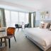 Auberge La Fontaine Aux Bretons in Pornic: bright hotel room with king bed, desk, and balcony seating